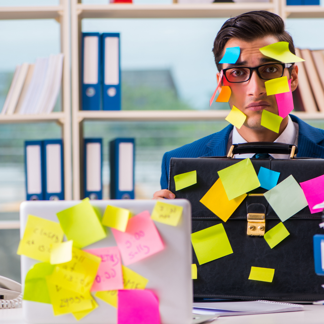 Ein Mann mit bunten PostIts im Gesicht und auf 2 Laptops die vor ihm stehen